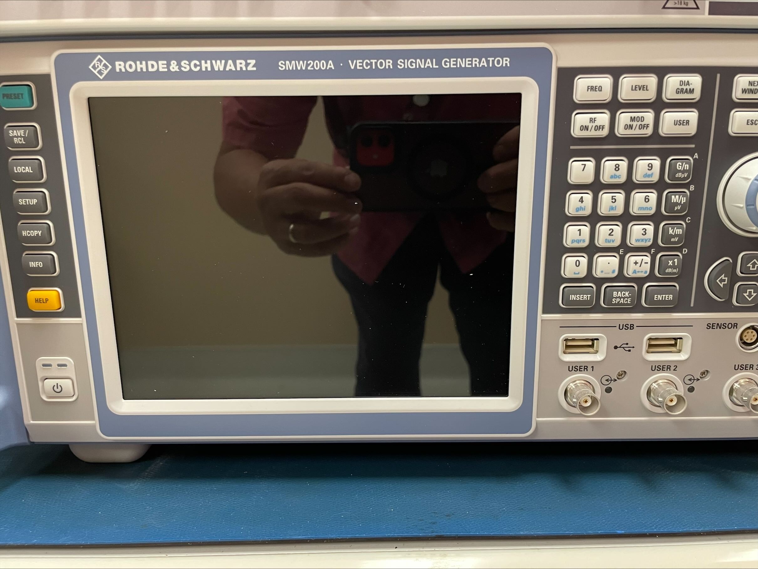 Close-up of a Rohde & Schwarz SMW200A Vector Signal Generator showing the screen, control buttons and various ports.